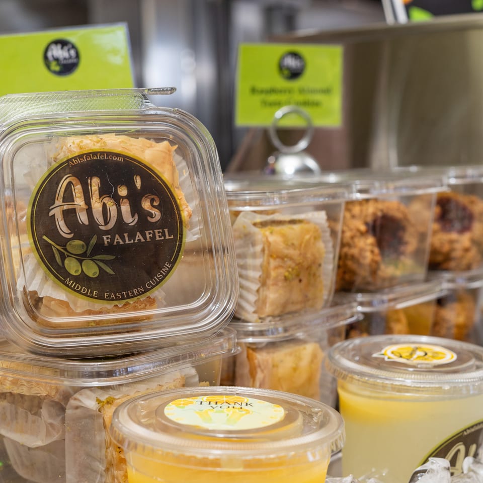 Abi's Falafel baklava and drinks in plastic containers on display.