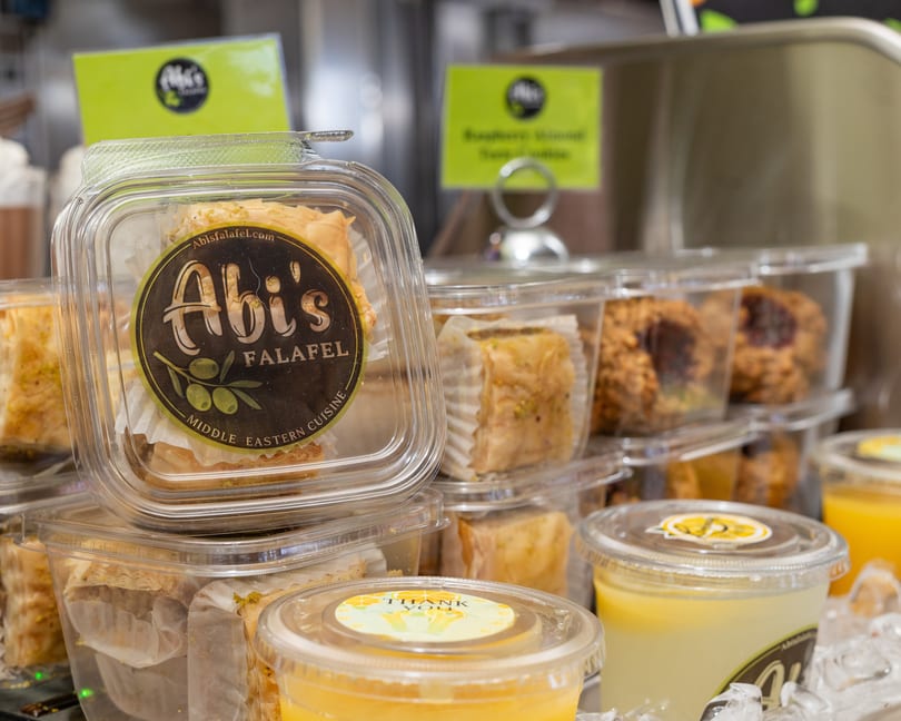 Abi's Falafel baklava and drinks in plastic containers on display.