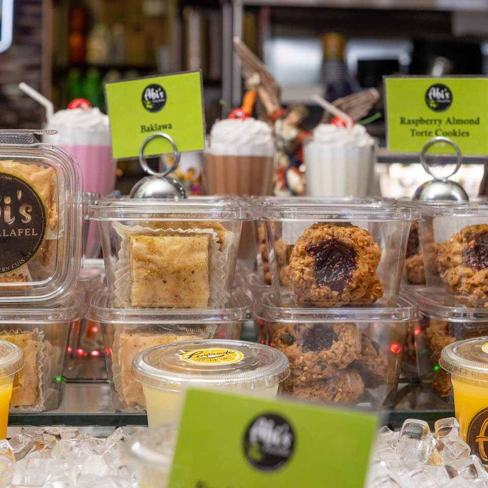 Abi's Falafel baklava, raspberry almond torte cookies, and drinks displayed in a refrigerated case.